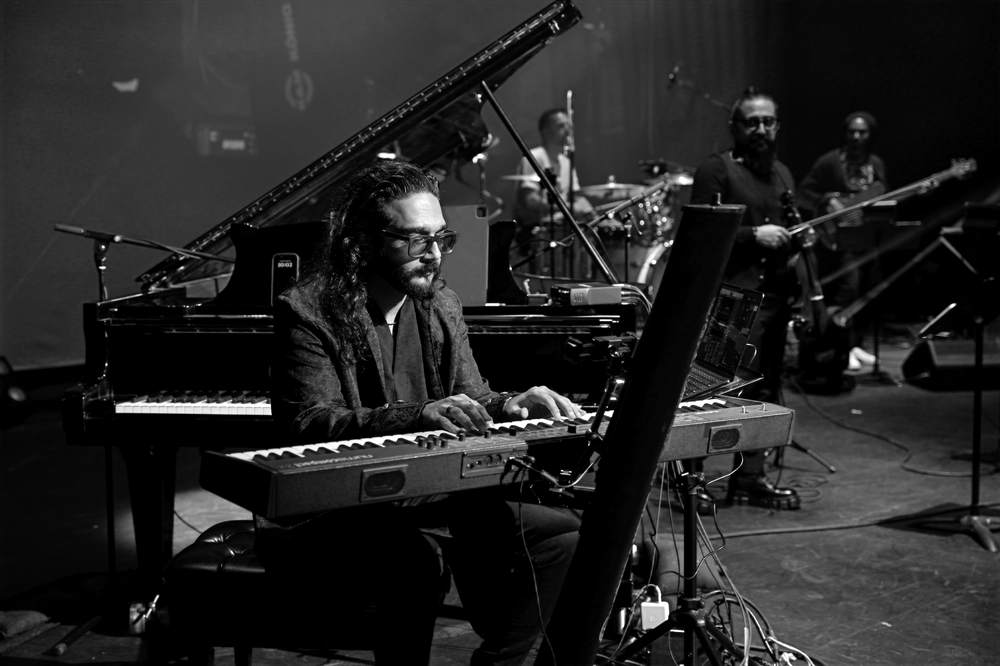 Behrooz Paygan playing keyboards on stage with his band